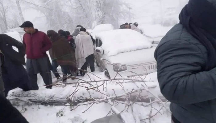 Image shows a car stranded in snow in Murree as people gather around it — Twitter