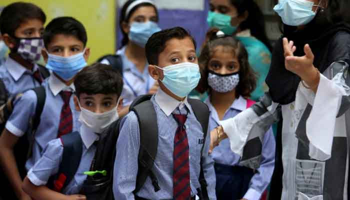 Students wearing face masks to prevent the spread of the coronavirus arrive at a primary school in this file photo. — AFP