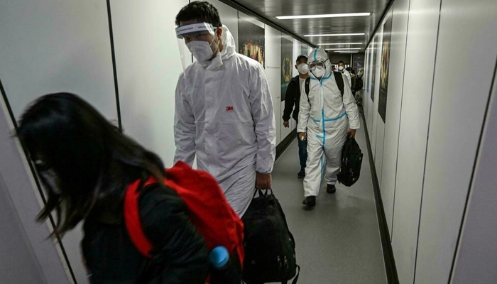 Passengers, some wearing full personal protective equipment, disembarking from their plane at Pudong International Airport in Shanghai on January 18, 2022. — AFP