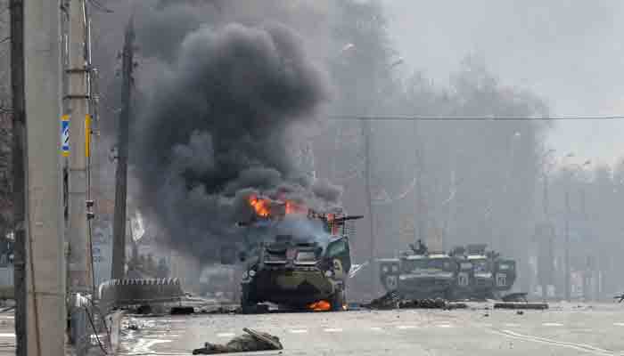 This photograph taken on February 27, 2022 shows a Russian Armoured personnel carrier (APC) burning next to an unidentified soldier´s body during a fight with the Ukrainian armed forces in Kharkiv.-AFP