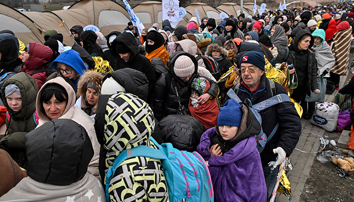 Refugees stand in line in the cold as they wait to be transferred to a train station after crossing the Ukrainian border into Poland, at the Medyka border crossing in Poland, on March 7, 2022. — AFP