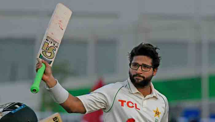 Pakistan´s Imam-ul-Haq (R) raises his bat after scoring 132 runs as he walks back to the pavilion at the end of the first day of the first Test cricket match against Australia at the Pindi Cricket Stadium in Rawalpindi on March 4, 2022. -AFP