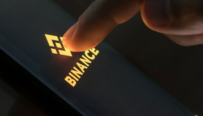 Person touching the binance icon on a screen. — Shutterstock