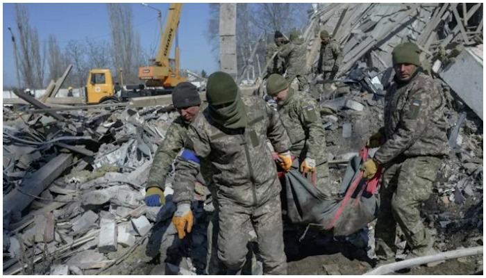 Ukrainian soldiers carried a comrades body out of debris Saturday at a military school hit by Russian rockets in Mykolaiv. Photo: AFP