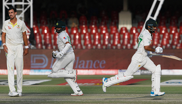 Pakistans Abdullah Shafique (R) and Pakistans Azhar Ali (2L) run between the wickets during the second day of the third and final Test cricket match between Pakistan and Australia at the Gaddafi Cricket Stadium in Lahore on March 22, 2022. — AFP