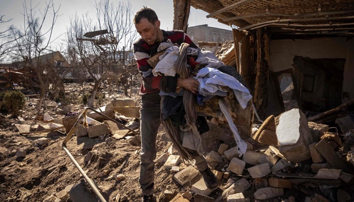 A man collects clothes from a damaged house in the city of Zhytomyr, northern Ukraine, on March 23, 2022. — AFP/File