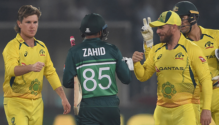 Australias captain Aaron Finch (R) and teammate Adam Zampa (L) greet with Pakistans Zahid Mehmood (C) after winning the first one-day international (ODI) cricket match between Pakistan and Australia at the Gaddafi Cricket Stadium in Lahore on March 29, 2022. — AFP