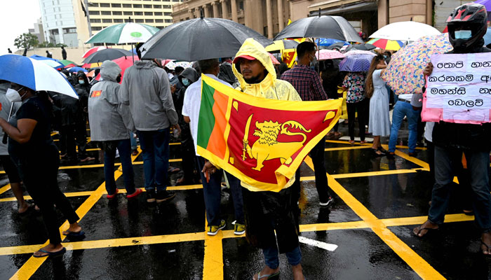 A demonstrator holds a Sri Lankas national flag as he takes part in a protest along with others against the economic crisis at the entrance of the president´s office in Colombo on April 10, 2022. Photo: AFP