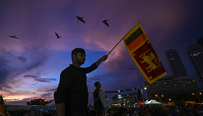 A protester holds a Sri Lanka’s national flag as he participates along with others in an anti-government demonstration near the president’s office in Colombo on April 17, 2022, demanding the resignation of President Gotabaya Rajapaksa over the country’s crippling economic crisis. — AFP