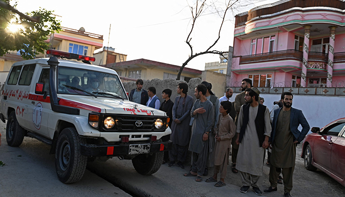 Onlookers stand next to an ambulance carrying victims near the site of a blast in Kabul on April 29, 2022. — AFP