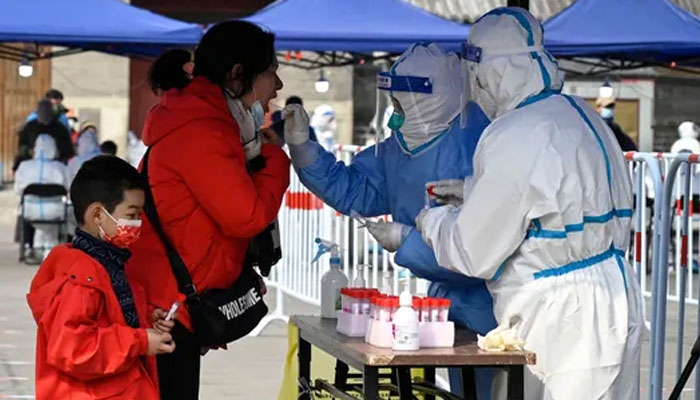 A healthcare worker takes a swab sample from a woman to be tested for the COVID-19 in Beijing. Photo: AFP