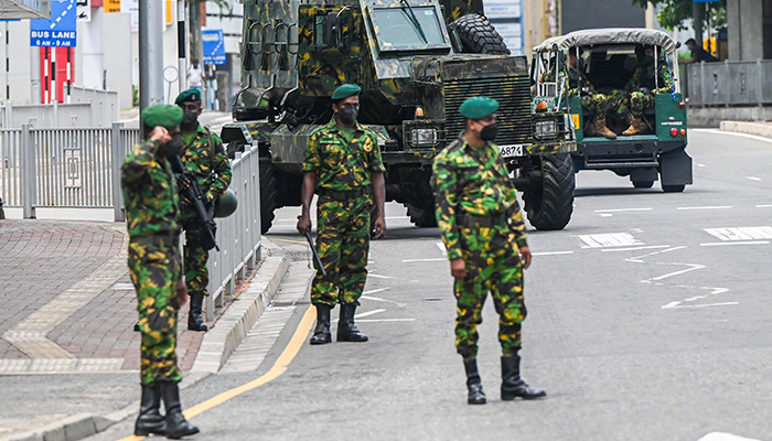 Soldiers stand guard near an armoured vehicle at a checkpoint in Colombo on May 11, 2022. — AFP