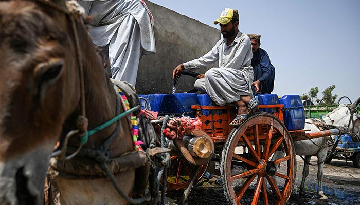 In this picture taken on May 11, 2022, vendors fill cans with drinking water on their donkey carts from a water supply plant for selling during a heatwave in Pakistans hottest city of Jacobabad in southern Sindh province. — AFP