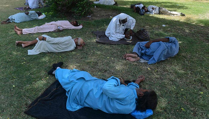 Men take nap under the shade of a tree at a public park during a hot summer day in Karachi on May 13, 2022. — AFP