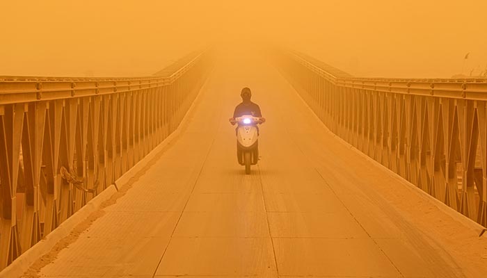 A motorist drives a scooter along a bridge in the city of Nasiriyah in Iraq´s southern Dhi Qar province on May 16, 2022 amidst a heavy dust storm. — AFP