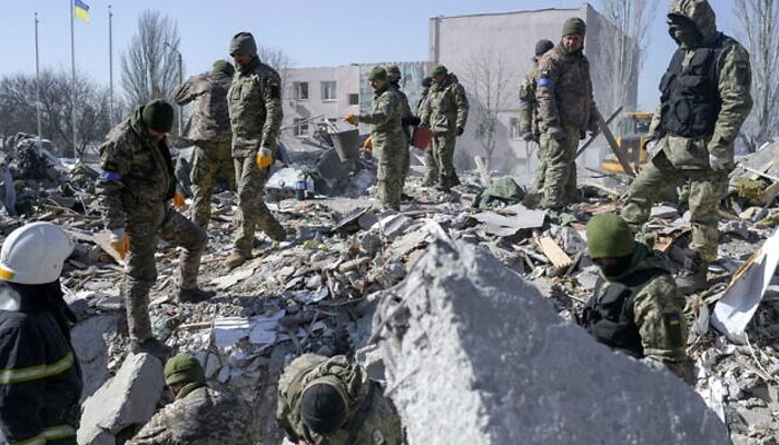 Ukrainian soldiers search for bodies in the debris at the military school hit by Russian rockets the day before, in Mykolaiv, southern Ukraine, on March 19, 2022. Photo: AFP