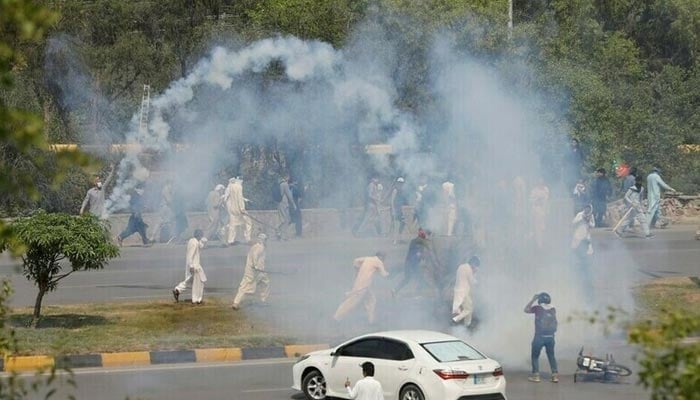PTI activists run with batons amid the tear gas smokes fired by police to prevent them from attending the protest march in Islamabad on May 26, 2022. — Reuters/File