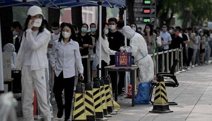People queue at a swab collection site to test for the COVID-19 coronavirus in Beijing on June 13, 2022. — AFP