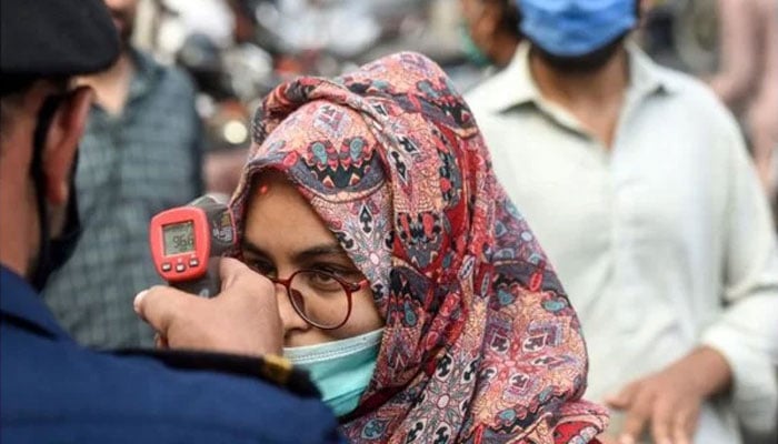 Un funzionario del centro commerciale (L) controlla la temperatura corporea di un cliente per lo shopping prima di Eid-ul-Fitr a Karachi.  — File AFP