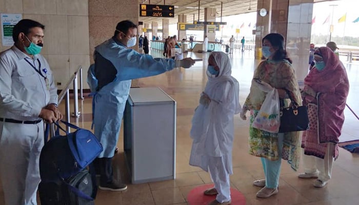 A health worker checks the temperature of a passenger at Karachi airport. -Picture Gulf Today