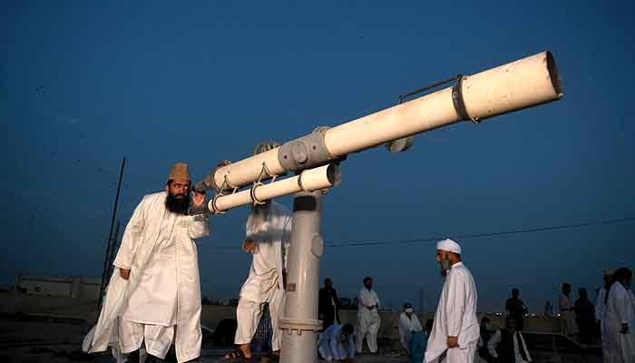 Maulana Syed Abdul Khabir Azad uses a telescope to sight the moon. -APP/file