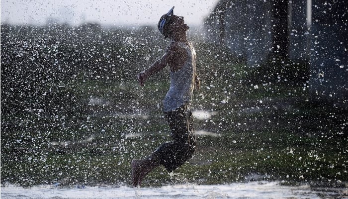 A youth enjoys splashing about in the rain in this AFP file photo by Asif Hassan.