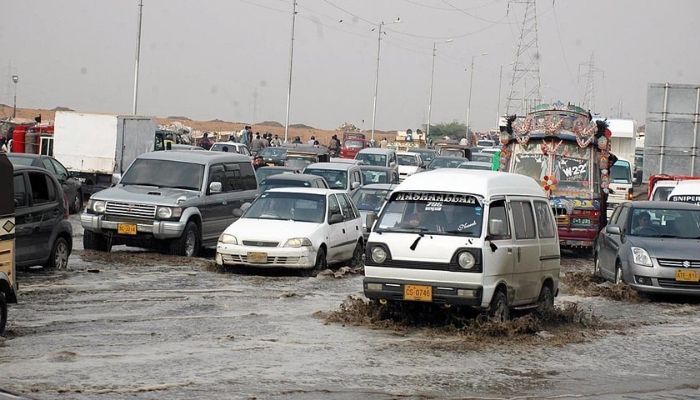Vehicles pass through rainwater accumulated at the Korangi Crossing area of Karachi. Photo: APP
