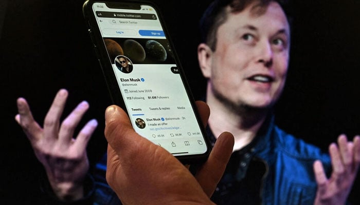 In this file photo illustration, a phone screen displays the Twitter account of Tesla chief Elon Musk with a photo of Musk in the background in Washington, DC on April 14, 2022. Photo: AFP