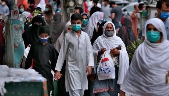 Cittadini mascherati attraversano una strada affollata in Pakistan in questa foto del file AFP.