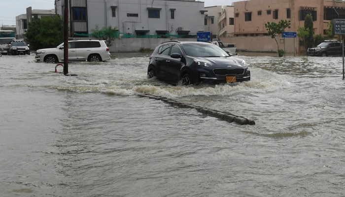 Commuters drive through a flooded street following heavy monsoon rains in Karachi on July 26, Photo: AFP/file