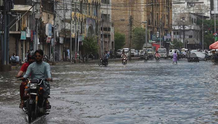 Commuters drive through a flooded street after heavy monsoon rainfall in Karachi on July 25, 2022. Photo: AFP