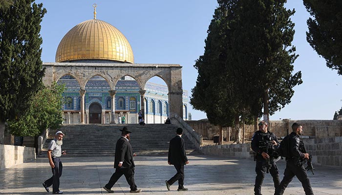 Israeli security forces protect ultra-Orthodox Jewish men as they walk past the Dome of the Rock mosque at the Al-Aqsa compound in Jerusalem amidst hightened tensions between Israel and Palestinian militants in the Gaza strip on August 7, 2022. — AFP