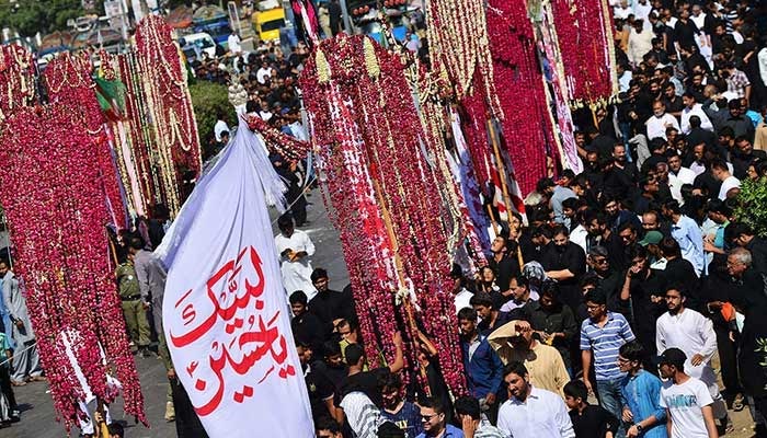 Mourners carry religious flags while marching during a procession on Muharram 8 in Karachi. — AFP/File