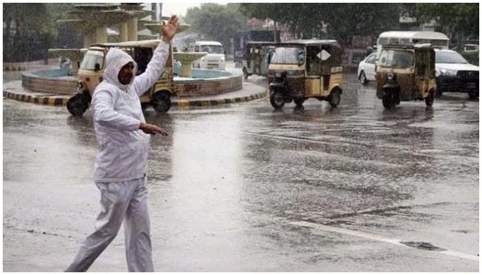 Image showing a traffic warden giving directions to cars amid rain on the streets of Karachi. Screengrab via Geo News/ file