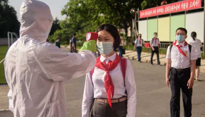 A student has her temperature taken as part of anti-COVID-19 procedures before entering a school in Pyongyang on June 22, 2021. —AFP