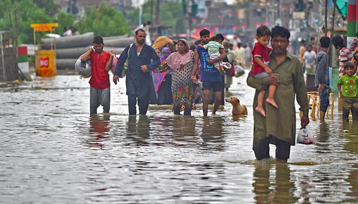 People walk across a flooded street following heavy rainfall in Karachi. — AFP/File