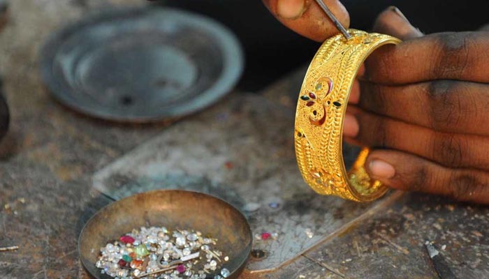 A workers adds finishing touches to a gold bangle at his workshop. — AFP/File