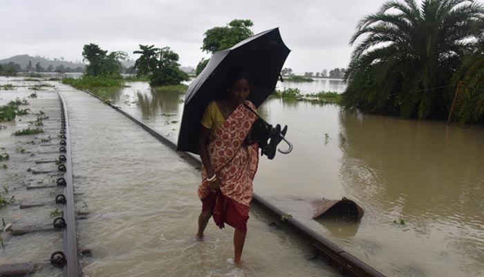 A woman walks through a flooded railway track in India. — AFP/File