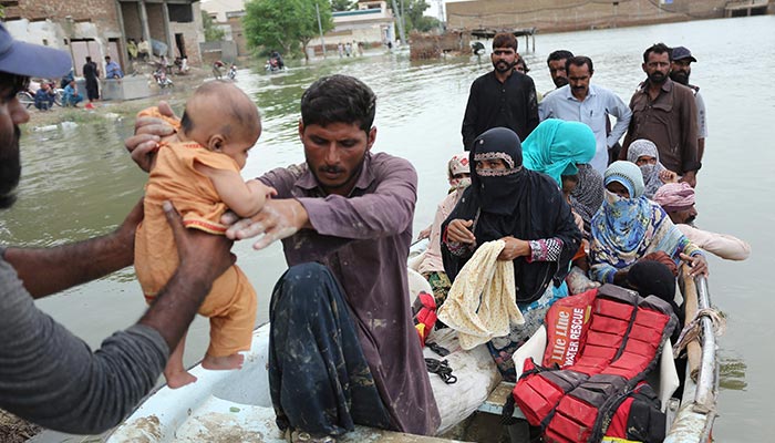 Residents arrive in a boat to a safer place after being evacuated following heavy monsoon rainfall in the flood affected area of Rajanpur district in Punjab province on August 24, 2022. — AFP