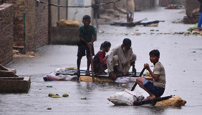 Residents use rafts to make their way along a waterlogged street in a residential area after a heavy monsoon rainfall in Hyderabad on August 24, 2022. — AFP