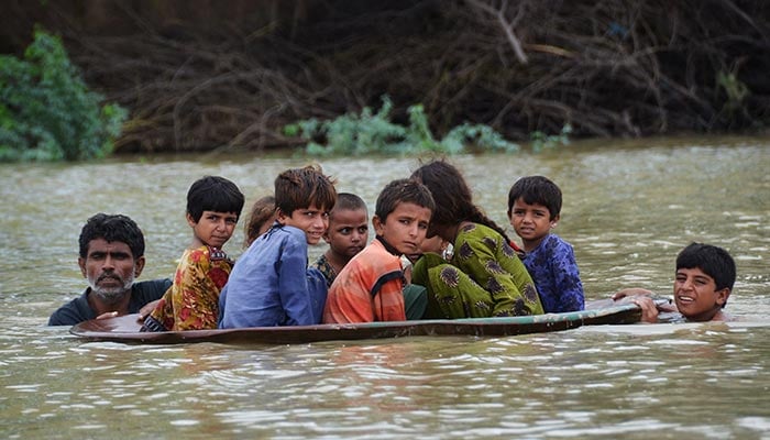 A man rescues his children during flooding in Sindh. — AFP