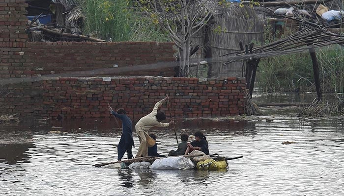 Children use a raft to make their way in a flooded area after heavy monsoon rains on the outskirts of Sukkur, Sindh province, on August 27, 2022. — AFP