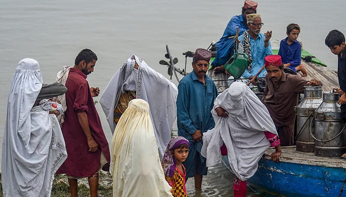 Stranded people are evacuated on boats from flood affected areas after heavy monsoon rains in Sukkur, Sindh province, on August 27, 2022. — AFP