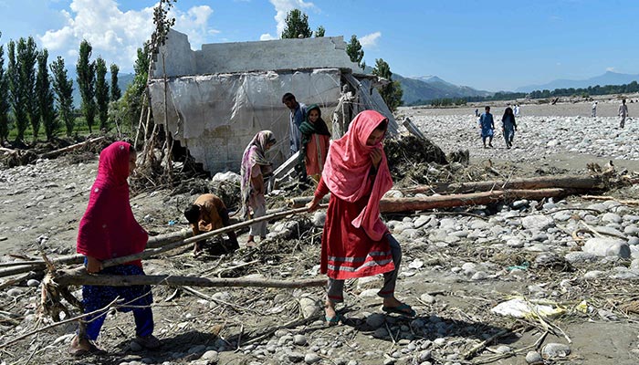Girls carry wood near a damaged house along a river following heavy monsoon rains in Mingora, a town in Pakistan´s northern Swat valley on August 28, 2022. — AFP