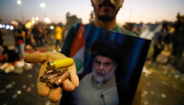 A supporter of Iraqi Shiite cleric Moqtada Sadr carries bullet casings and a spent shotgun shell in the capital Baghdad´s Green Zone, on August 29, 2022. — AFP