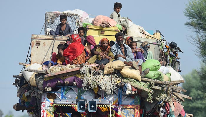 Displaced people sit on a tractor with their belongings as they make their way to reach safer place camp after fleeing from their flood hit homes following heavy monsoon rains in Shikarpur of Sindh province on August 30, 2022. — AFP
