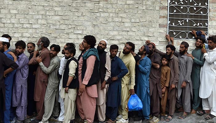 Flood-affected people stand in a queue as they wait to receive food packets at Bahrain town of Swat valley in Khyber Pakhtunkhwa province on August 31, 2022. — AFP
