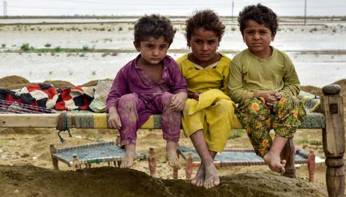 Children are sitting on a charpoy in a flood-hit area. Photo: UNICEF/file