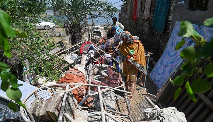 Mureed Hussain helps other family members to dry the dowry belongings of his daughter Nousheen, which were damaged by flood waters at his house in Fazilpur, Rajanpur district of Punjab province on September 3, 2022. — AFP