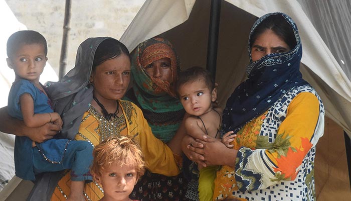 Flood-affected people stand outside a tent at a makeshift camp after heavy monsoon rains in Jaffarabad district, Balochistan province on September 3, 2022. — AFP